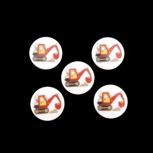 May include: Five white round buttons featuring a red and yellow cartoon excavator design. The excavator is digging dirt with its shovel.