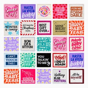 Op de afbeelding: Een verzameling van vijfentwintig vierkante geborduurde patches met diverse kleurrijke ontwerpen en zinnen, waaronder Shake it off, Hasta la vista baby, Winter is coming, All I want for Christmas is you, Best gift ever, Shine bright en Groovy baby yeah.