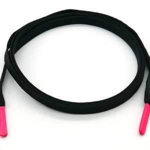 Pode incluir: Cadarços pretos para sapatos com aglets rosa. Os cadarços são planos e têm uma textura lisa.