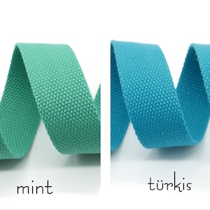 May include: Two rolls of woven cotton webbing, one in mint green and one in turquoise blue. The webbing is coiled and the ends are visible.