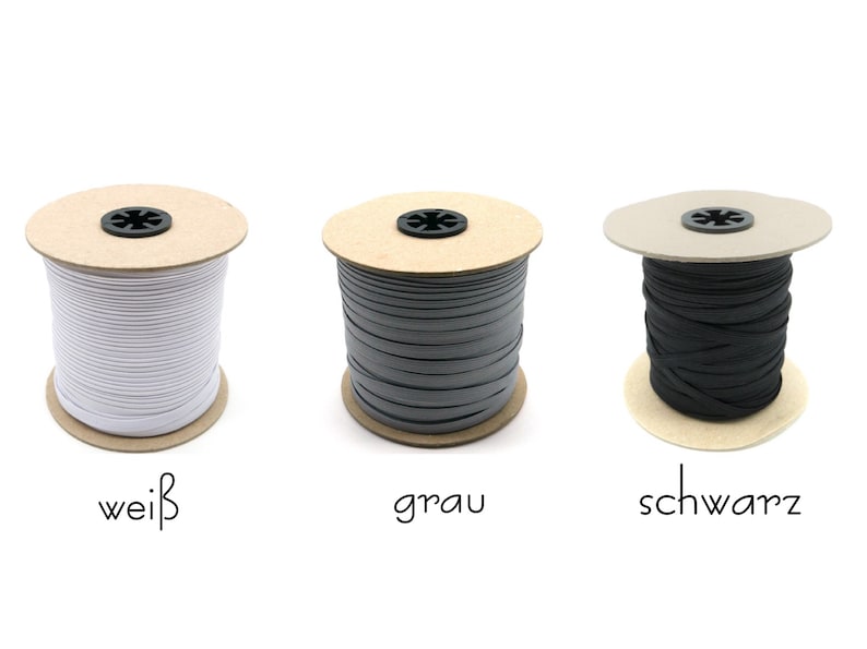 May include: Three spools of elastic cord, one white, one gray, and one black, each wound around a cardboard spool with a label underneath. The labels read "wei&szlig;", "grau", and "schwarz".