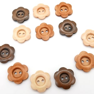 May include: A collection of 12 wooden flower-shaped buttons in various shades of brown, beige, and natural wood. The buttons have two holes each and are arranged in a circle on a white background.