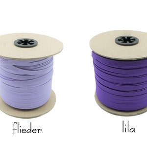 May include: Two spools of elastic, one lilac and one purple, on a white background. The spools are labeled "flieder" and "lila".