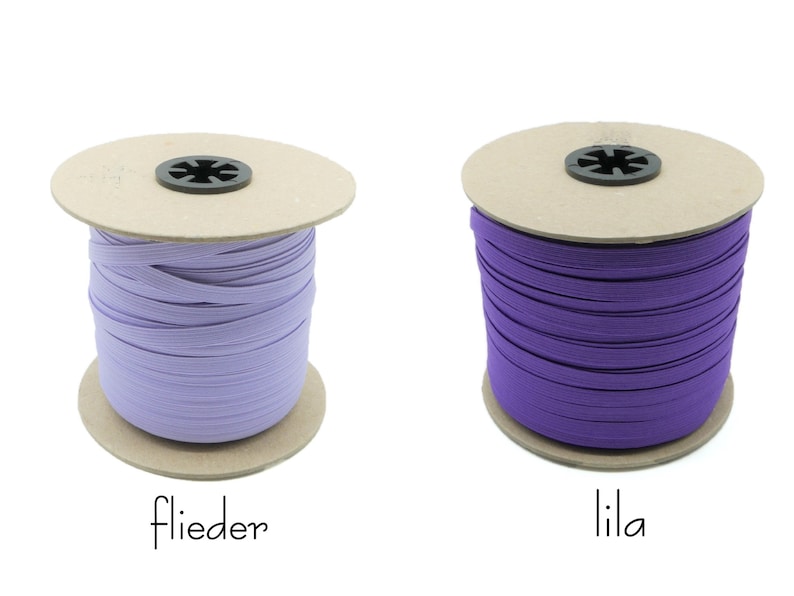 May include: Two spools of elastic, one lilac and one purple, on a white background. The spools are labeled "flieder" and "lila".