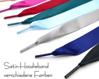 Peut inclure: Un ensemble de lacets en satin de différentes couleurs, dont le rose, le rouge, le bleu sarcelle, le bleu clair, le gris, le bleu marine et le noir. Les lacets sont disposés en rangée, les extrémités pointant vers la droite. Le texte "Satin-Hoodie-band verschiedene Farben" est visible en bas de l'image.