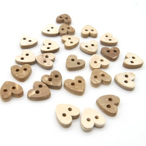 Könnte beinhalten: Eine Sammlung von 20 herzförmigen Knöpfen in Braun- und Beigetönen. Die Knöpfe haben jeweils zwei Löcher und sind aus natürlichen Materialien gefertigt.