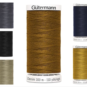 Puede incluir: Cuatro carretes de hilo Gütermann en diferentes colores: gris oscuro, negro, beige y amarillo mostaza. Cada carrete está etiquetado con "Gütermann Denim 100 m - 110 yds/vgs".
