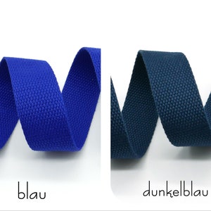 May include: Two samples of woven cotton webbing, one blue and one dark blue. The webbing is folded in a W shape.