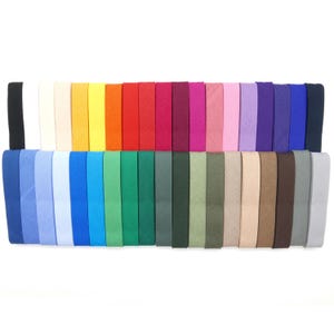 Può includere: Una collezione di strisce di sbieco colorate in una varietà di tonalità, tra cui nero, bianco, giallo, arancione, rosso, rosa, viola, blu e verde. Le strisce sono disposte in due file, mostrando la diversa tavolozza di colori.