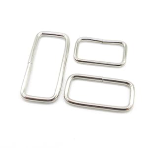 Könnte beinhalten: Drei silberne D-Ringe aus Metall in verschiedenen Größen. Die Ringe sind glatt und haben eine polierte Oberfläche.