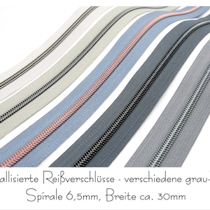 Könnte beinhalten: Eine Auswahl von 7 metallischen Reißverschlüssen in verschiedenen Grautönen, darunter ein helles Rosa. Die Reißverschlüsse haben einen Durchmesser von 6,5 mm und eine Breite von 30 mm. Der Text auf dem Bild lautet "Metallizerte Reißverschlüsse - verschiedene grau-Töne Spirale 6,5mm, Breite ca. 30mm".