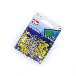 Può includere: Una confezione di spilli Prym con testa di vetro. Gli spilli hanno la testa gialla e sono contenuti in una scatola di plastica trasparente. La confezione include il testo "Glaskopfstecknadeln" e "Glass-headed pins". La confezione indica che gli spilli sono lunghi 42 mm e pesano 20 g.