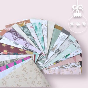 May include: A fan of patterned paper sheets with various winter and holiday designs. The papers feature illustrations of trees, stars, and other festive motifs in colors like green, brown, and pink. A decorative ornament graphic is in the upper right corner.
