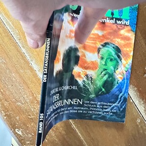 Peut inclure: Une couverture de livre avec une image en noir et blanc d'une femme aux cheveux verts. Le titre du livre est "Der Satansbrunnen" et le sous-titre est "Churchill & Churchill". Le livre fait partie d'une série et est le volume 105.
