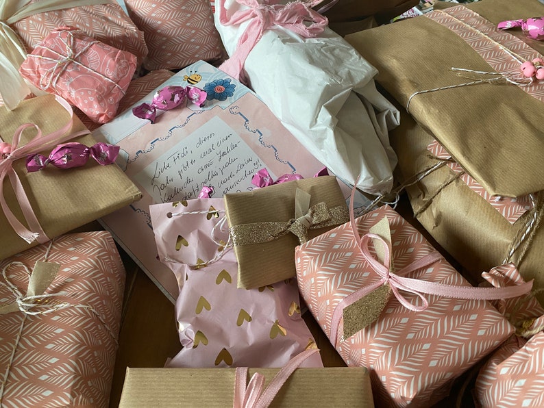 May include: An assortment of wrapped gifts in various sizes and patterns. The gifts are wrapped in pink, white, and brown paper, some with gold accents. Pink ribbons and bows adorn the packages, creating a festive and celebratory feel.