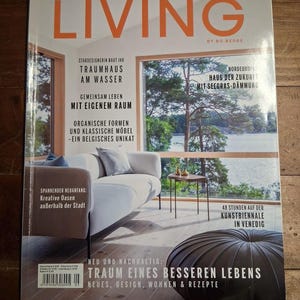 May include: A magazine cover with the title "SCANDINAVIAN LIVING" in orange letters. The cover features images of interior design, a lakeside view, and furniture. Text includes phrases like "Dream House on the Water" and "New and Sustainable: Dream of a Better Life."