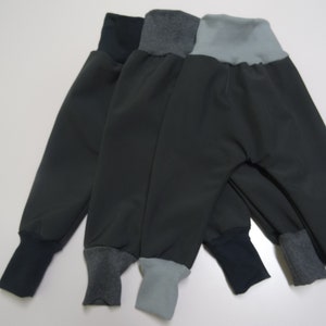 May include: Three pairs of dark gray sweatpants with contrasting colored cuffs. The cuffs are gray, blue, and light blue.