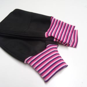 May include: Black fabric arm warmers with pink and purple striped cuffs.