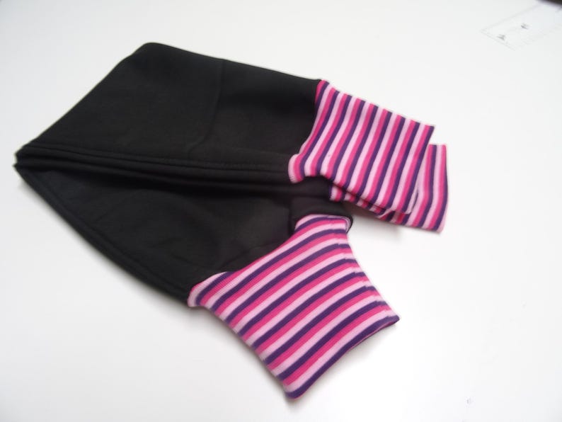 May include: Black fabric arm warmers with pink and purple striped cuffs.