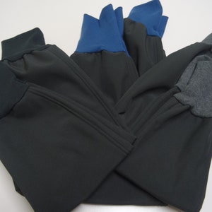 May include: Three pairs of black sweatpants with different colored cuffs. One pair has blue cuffs, one pair has gray cuffs, and one pair has black cuffs.