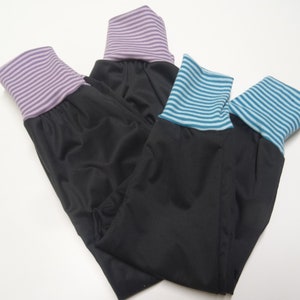 May include: Three pairs of black leggings with different colored striped cuffs. The cuffs are purple, blue, and teal.
