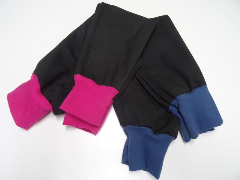 May include: Two pairs of black leggings with contrasting colored cuffs. One pair has pink cuffs and the other has blue cuffs.