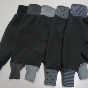 May include: Five pairs of gray fleece pants with different colored cuffs. The cuffs are navy blue, gray, light gray, gray with black stars, and gray with navy blue stripes.