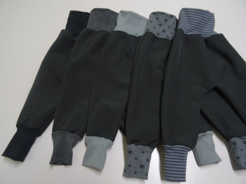 May include: Five pairs of gray fleece pants with different colored cuffs. The cuffs are navy blue, gray, light gray, gray with black stars, and gray with navy blue stripes.