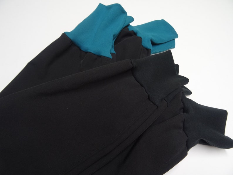 May include: Black pants with teal blue cuffs. The pants are made of a soft, stretchy fabric and have a relaxed fit.