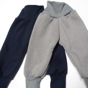 以下が含まれることがあります： グレーとネイビーの2本のスウェットパンツ。両方のパンツは、ゴム製のギャザーウエストバンドとカフ付きのレッグを持っています。