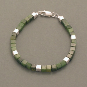 Könnte beinhalten: Ein grünes Jade- und Silberarmband mit quadratischen Perlen. Das Armband besteht aus grünen Jade-Steinen mit silbernen Akzenten.