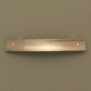 May include: A curved, silver-toned metal drawer pull with rounded edges and two small, round, silver-toned knobs.