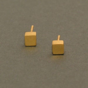 May include: A pair of gold square stud earrings. The earrings are small and have a brushed finish.