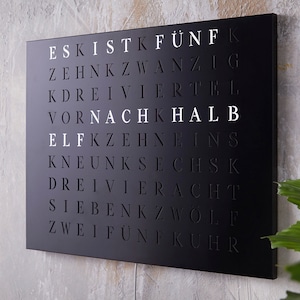 Puede incluir: Arte de pared de metal negro con letras blancas que deletrean las palabras alemanas para los números del uno al veinte. Las palabras están dispuestas en una cuadrícula.
