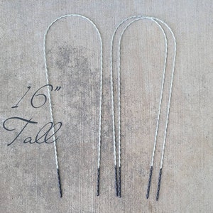 May include: Four 16-inch tall silver wire hoops with black tips. The hoops are twisted and are arranged in two pairs.