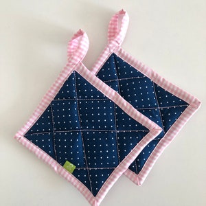 May include: Two blue and white polka dot pot holders with pink and white gingham trim and loops. The pot holders are quilted and have a green label with the letter "D" on one of them.