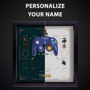 May include: Framed Nintendo GameCube controller display. The blue controller is centered, with diagrams and character art on either side. Text at the top reads "PERSONALIZE YOUR NAME". The frame is black.