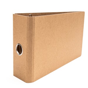 May include: A brown cardboard binder with a metal ring mechanism. The binder is closed and has a plain, unadorned front cover.