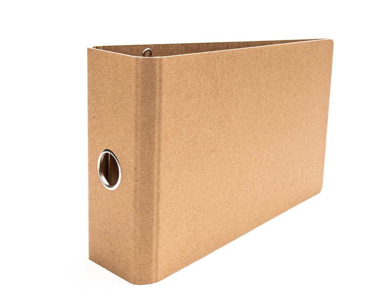 May include: A brown cardboard binder with a metal ring mechanism. The binder is closed and has a plain, unadorned front cover.