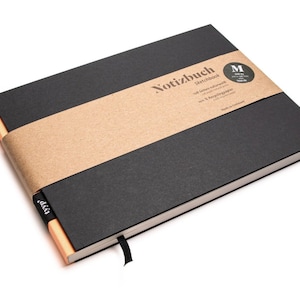 Könnte beinhalten: Ein schwarzes Notizbuch mit einem Kraftpapierband und einem schwarzen Lesebändchen. Das Cover trägt den Text "Notizbuch Sketchbook" und einen runden Aufkleber mit der Größenangabe. Die Seitenränder sind hellorange.