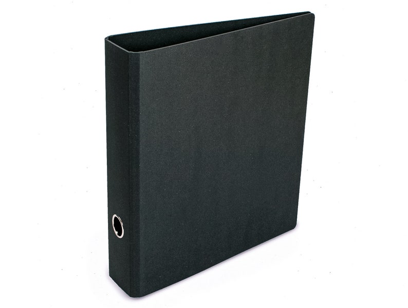 May include: A black binder with a metal ring mechanism. The binder is closed and has a smooth, textured surface.
