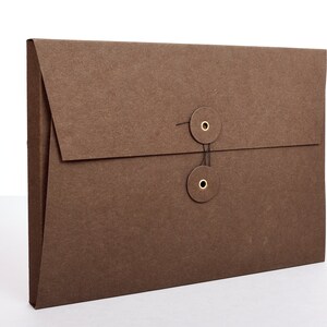 May include: A brown paper envelope with a flap closure and two brass eyelets with a black string threaded through them.