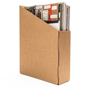 May include: A brown cardboard magazine holder with a slanted opening for inserting magazines. The holder is empty.