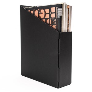 May include: Black magazine holder with a triangular opening. The holder is made of a sturdy material and has a sleek, modern design.