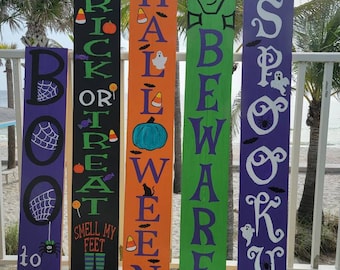 May include: Four wooden Halloween signs with painted designs. The signs read "Boo to you", "Trick or Treat", "Happy Halloween", and "Beware Spooky".