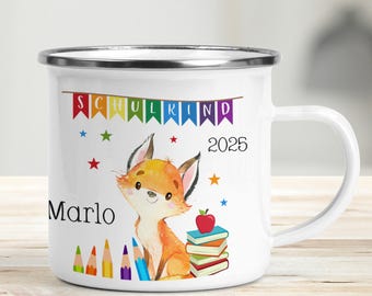 May include: White enamel mug with a colorful fox illustration, a stack of books, and pencils. The mug has a silver rim and handle. The text "SCHULKIND 2025" and "Marlo" are printed on the mug.
