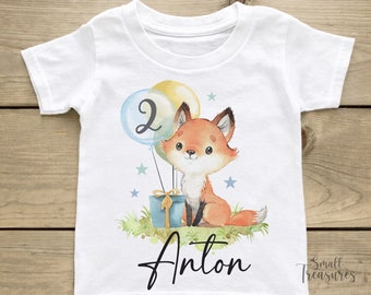 Op de afbeelding: Wit T-shirt met een illustratie van een vos en ballonnen. De ballonnen zijn blauw, geel en groen. De vos is oranje en heeft een zwarte neus en ogen. Het nummer 2 staat op een van de ballonnen. De tekst "Anton" is onder de illustratie gedrukt.