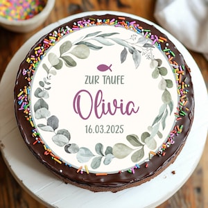 Könnte beinhalten: Ein runder Schokoladenkuchen mit dekorativem Zuckerguss. Der Kuchen ist mit einem weißen Kreis mit einem floralen Kranz, dem Namen "Olivia" und dem Datum "16.03.2025" belegt. Bunte Streusel säumen den Rand.