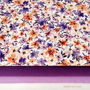 Puede incluir: Una tela blanca con estampado floral con flores naranjas y moradas. La tela está superpuesta sobre dos telas moradas.