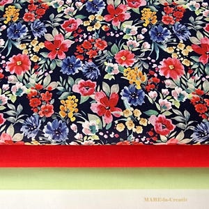 Könnte beinhalten: Ein marineblauer Stoff mit einem bunten Blumenmuster. Der Stoff zeigt eine Vielzahl von Blumen in Rot-, Rosa-, Gelb- und Blautönen. Der Stoff ist auf einem roten Stoff und einem hellgrünen Stoff geschichtet.